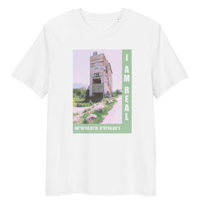 A decaying building sit in a barren landscape. "I AM REAL" and coordinates printed onto the shirt